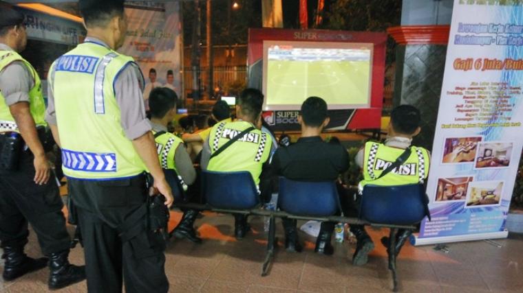 Sejumlah petugas kepolisian terlihat asyik menyaksikan pertandingan sepak bola di salah satu stand di Pelabuhan Merak. (Foto:TitikNOL)
