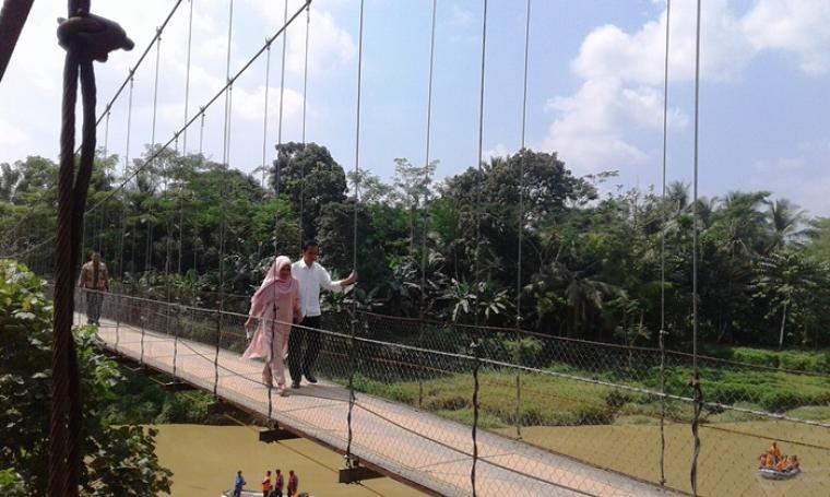Presiden Jokowi dan Ibu Negara, saat melintasi jembatan gantung di Kecamatan Kalanganyar, Kabupaten Lebak. (Foto:TitikNOL)