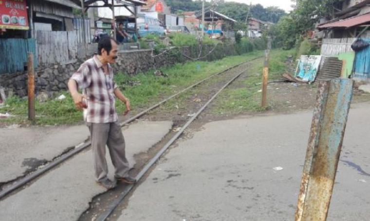 Seorang warga saat menunjukan perlintasaan kereta api tanpa palang pintu di Kelurahan Mekarsari, Kecamatan Pulomerak, Kota Cilegon. (Foto:TitikNOL)