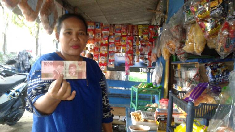 Ani menunjukan uang palsu pecahan seratus ribu yang dia peroleh dari dua pria yang tidak dikenal. (Foto: TitikNOL)