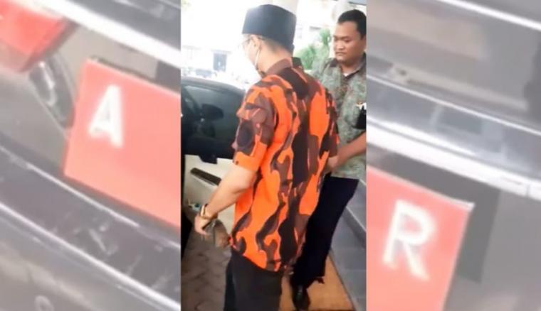 Foto tangkapan layar video yang viral yang menunjukan seorang pria mengenakan seragam ormas hendak menaikin mobil dinas Wali Kota Cilegon. (Foto: TitikNOL)
