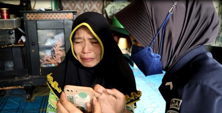 Ibu Rizki, Maimunah menangis haru saat melihat anaknya memakai seragam Polisi lewat video call. (Foto: TitikNOL)